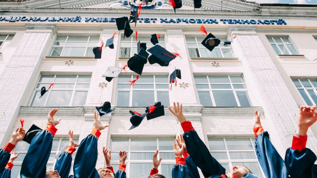 Studierende schmeißen ihre Abschlusshüte in die Luft